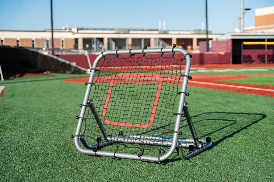 Silver baseball and softball rebounder with a red target on a practice field.